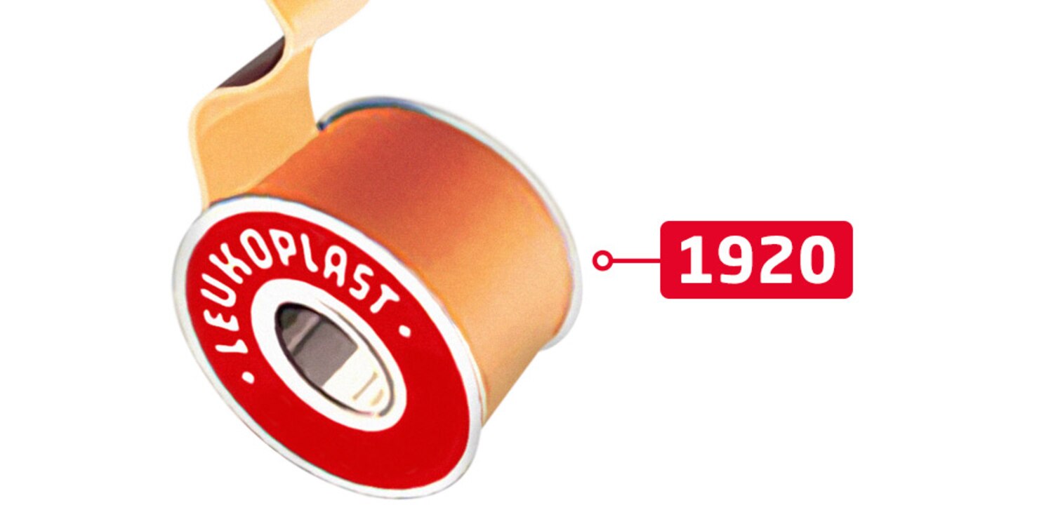 Naast de datum 1920 zien we een bovenaanzicht van de iconische rode Leukoplast-rol met zelfklevende hechtpleister.